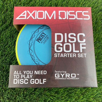 Axiom discs golf starter set box featuring a light blue proxy disc through the window, resting on artificial turf.