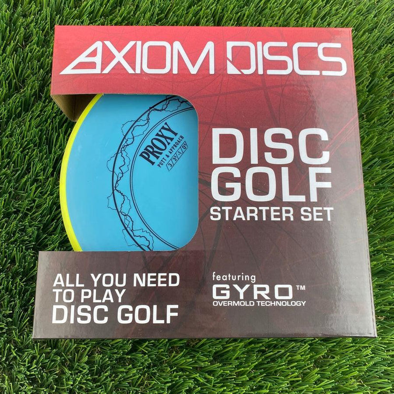 Axiom discs golf starter set box featuring a light blue proxy disc through the window, resting on artificial turf.
