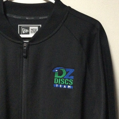 Black new era track jacket featuring a green and blue embroidered "dzdiscs team" logo on the chest.