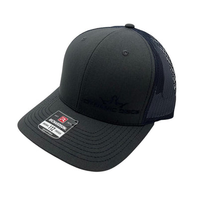 A black richardson 112 trucker snapback hat with a visible "dynamic discs" logo embroidered on the front.