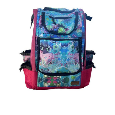 Carbella Designs backpack disc golf bag in mauve with a vibrant blue, purple, and green patterned front.