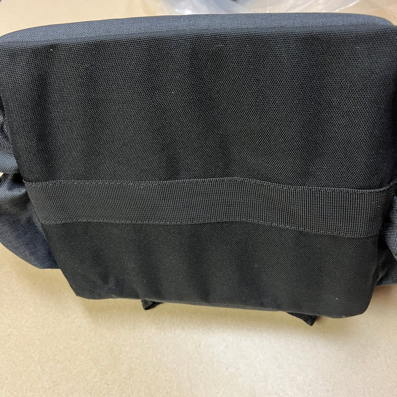 A close-up of a black textured fabric cooler disc golf bag with a horizontal nylon strap visible.