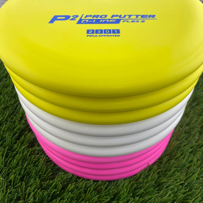 Stack of Discmania D-Line Flex 2 P2 Pro Putter golf discs in yellow, white, and hot pink colors.