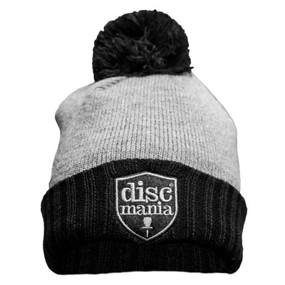 Two-toned Discmania fleece lined pom beanie with a light grey top, black brim, and embroidered Discmania badge.