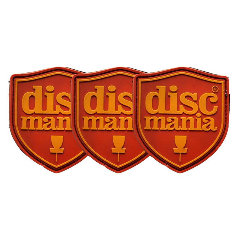 Three Discmania rubber shield patches with "Discmania" and a basket logo in orange on a red background.
