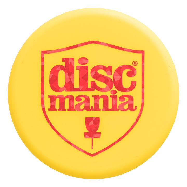 Round yellow Discmania mini marker disc with a red shield logo and geometric pattern.