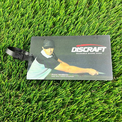 Black Discraft reusable scorecard with a detailed image of disc golfer Paul McBeth and an attached black plastic loop.