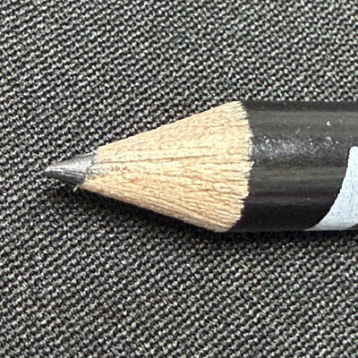 Black Discraft score keeping pencil with a sharp gray lead point against a textured gray surface.