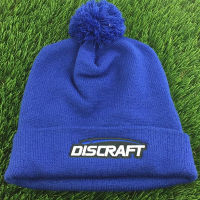 Blue knitted Discraft embroidered logo cuff pom beanie with a matching blue yarn pom pom on top.