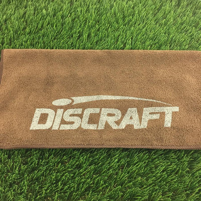 Brown microfiber golf towel with a white printed Discraft logo and a dark brown stitched border.