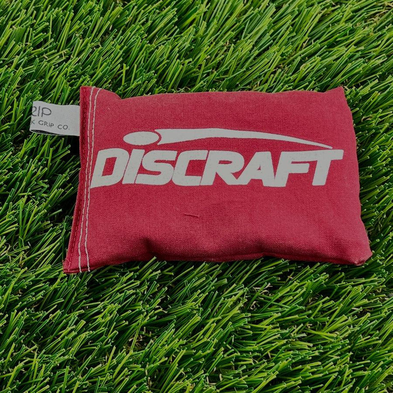 Crimson red Discraft Sportsack with a white logo and visible stitching along the edges, and a Grip Co. tag.
