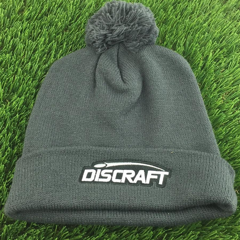 Dark gray knit Discraft embroidered logo cuff pom beanie with a matching gray pom on top.