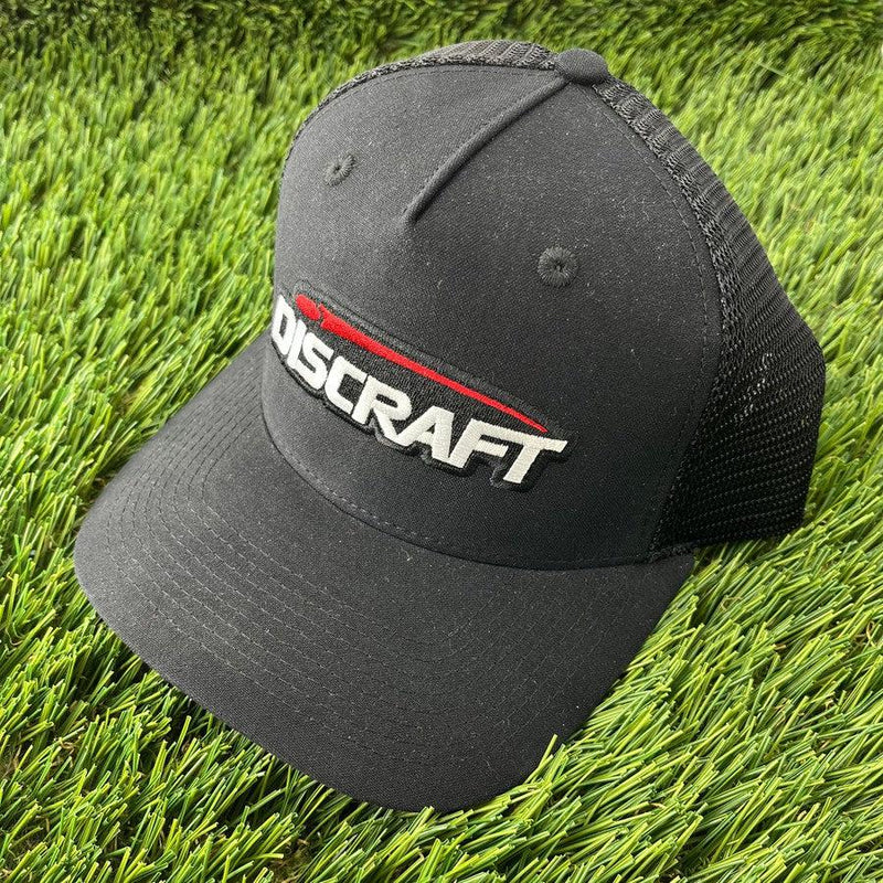 Black Discraft embroidered logo mesh snapback curved bill hat with a white and red stitched logo.