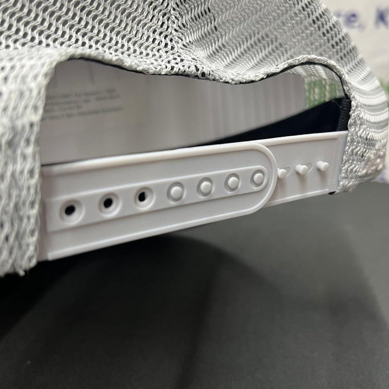 Close up of a gray mesh snapback hat showing the white plastic adjustable closure on the back.