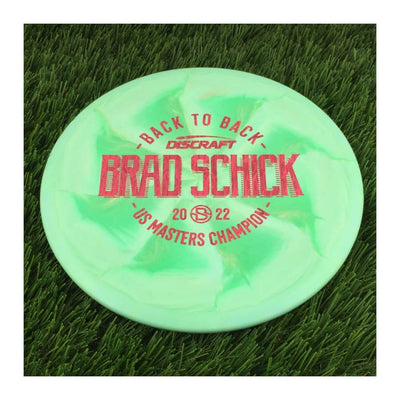 Solid green Discraft ESP Swirl FLX Buzzz 180g with a red Brad Schick 2022 US Masters Champion stamp.