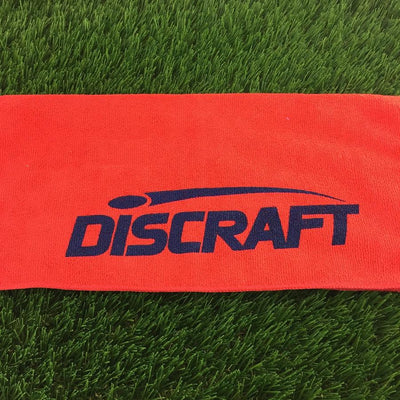 Bright orange Discraft microfiber golf towel featuring a prominent navy blue printed logo.