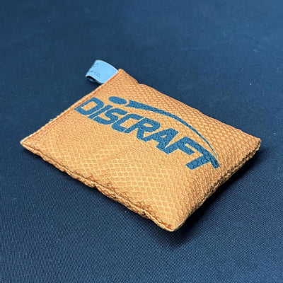 Orange Discraft Silky Feel Waffle Sportsack with a blue diagonal Discraft logo and an attached fabric tag.