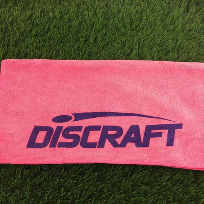 Pink microfiber golf towel featuring a boldly printed dark purple Discraft logo across the center.