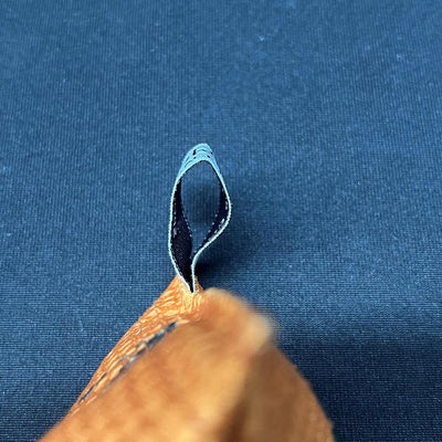 Edge of an orange brown Silky Feel Discraft Sportsack with a black and light blue patterned loop attached.