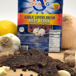 A blue DoubleG Garlic Lovers Dream Craft Beef Jerky package stands behind several dark, savory jerky pieces.