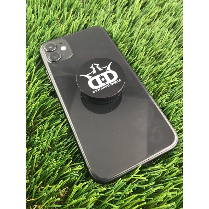 Black Dynamic Discs King DS PopSocket phone holder with a white crown logo on a dark grey cellphone.