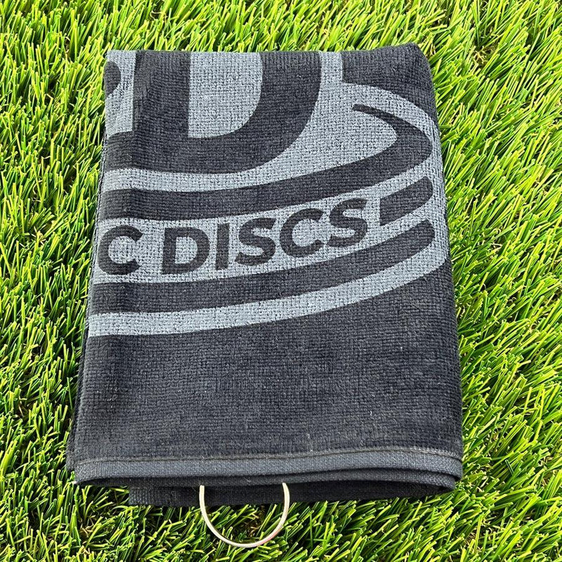 Folded black Dynamic Discs disc golf towel with a gray logo and a silver metal carabiner ring.