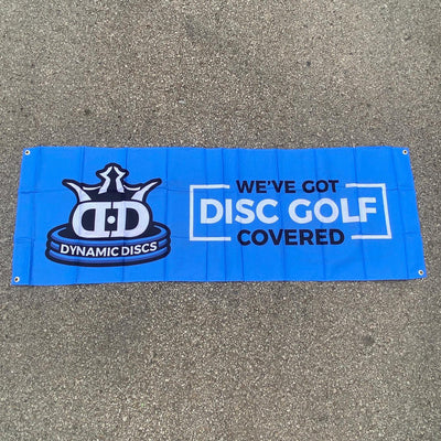 Blue Dynamic Discs fabric banner with a crown logo and "We've Got Disc Golf Covered" in white lettering.