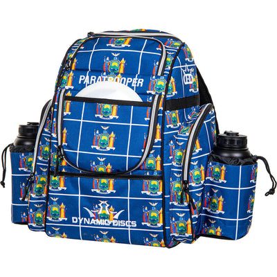 Blue Dynamic Discs Paratrooper backpack with a white grid pattern, multiple zippered pockets, and two black water bottles.