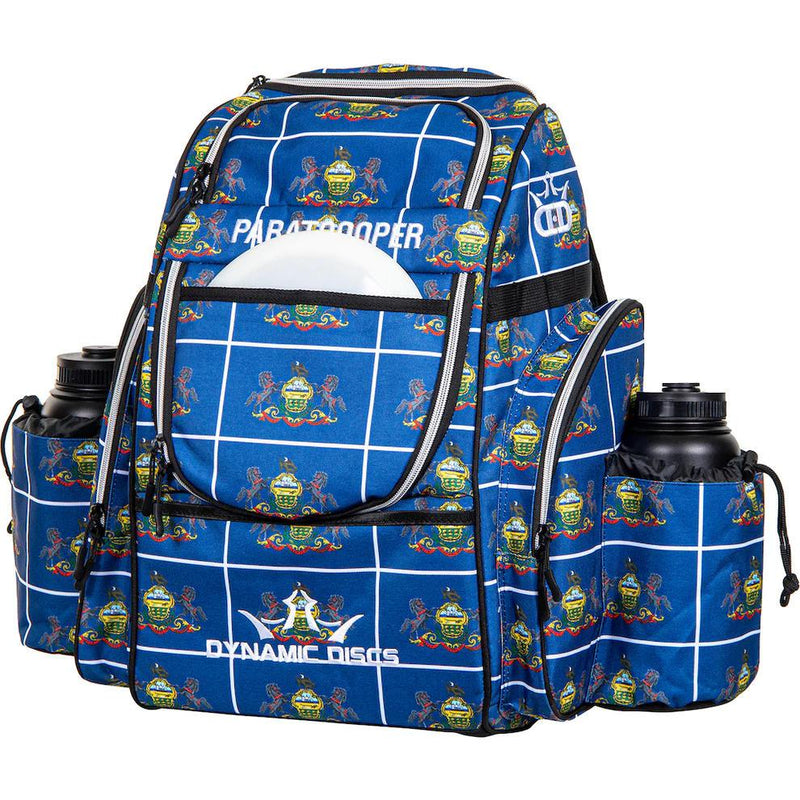 Blue Dynamic Discs Paratrooper backpack with a white grid pattern, colorful state seals, and two black water bottles.
