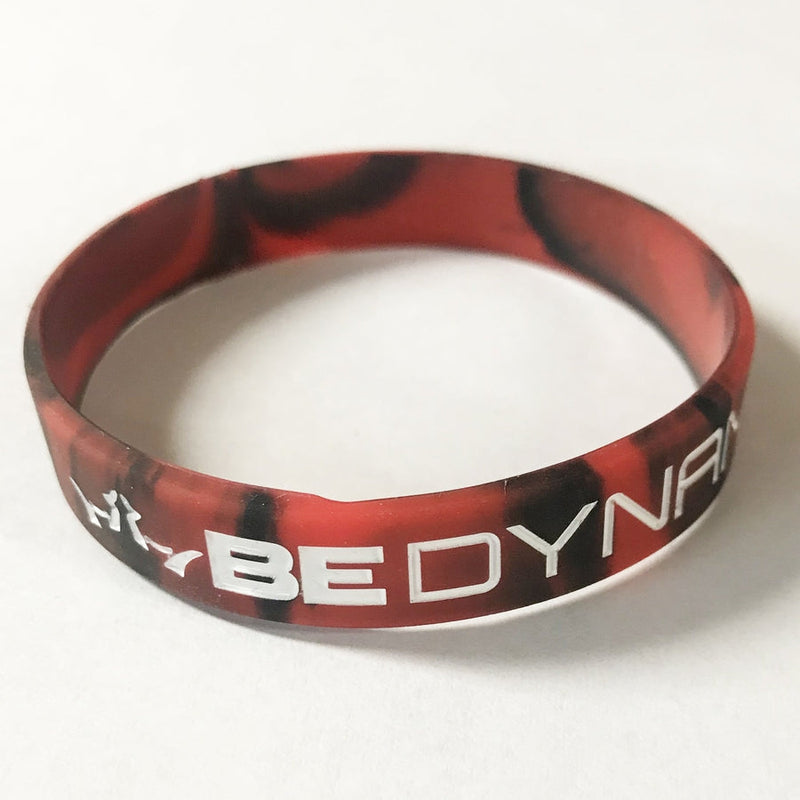 Red and black camouflage-patterned silicone Dynamic Discs wristband with white embossed "BE DYNAMIC" lettering.