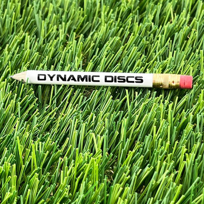 White Dynamic Discs pencil with a sharpened lead tip, a gold metal ferrule, and a pink eraser.