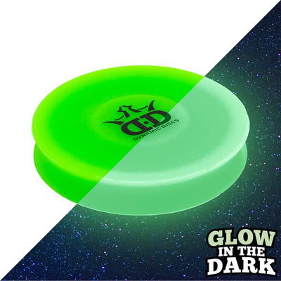 Green Dynamic Discs Zlinger disc golf mini, half brightly lit and half glowing in the dark.