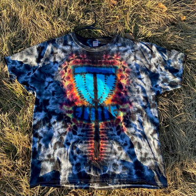 A black, blue, and gray tie-dye t-shirt features a vibrant central design of a disc golf basket with blue chains.