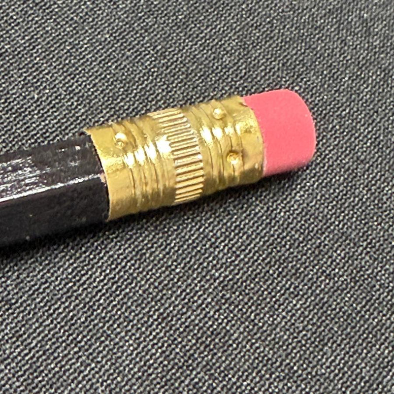 Black golf scoring pencil features a bright pink eraser and a shiny gold ferrule.
