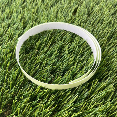 A bright green glow-in-the-dark tape with a white paper backing is curled into a circular shape.