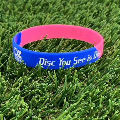A blue and pink silicone wristband with white "OZ Discs" and "Disc You See is Disc" text.