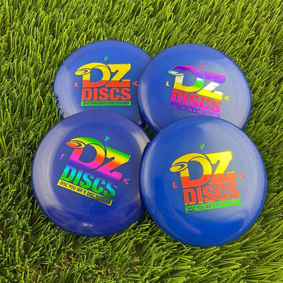 Four blue dzdiscs mini marker discs with colorful foil logos, resting on vibrant green artificial turf.