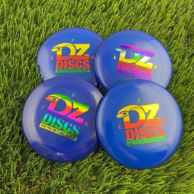 Four blue dzdiscs mini marker discs with colorful foil logos, resting on vibrant green artificial turf.