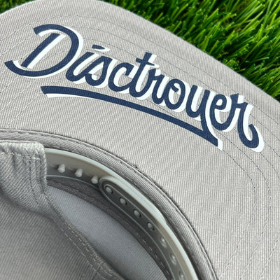Grey disctroyer flat bill snapback hat with dark blue and white logo, snap closure visible.