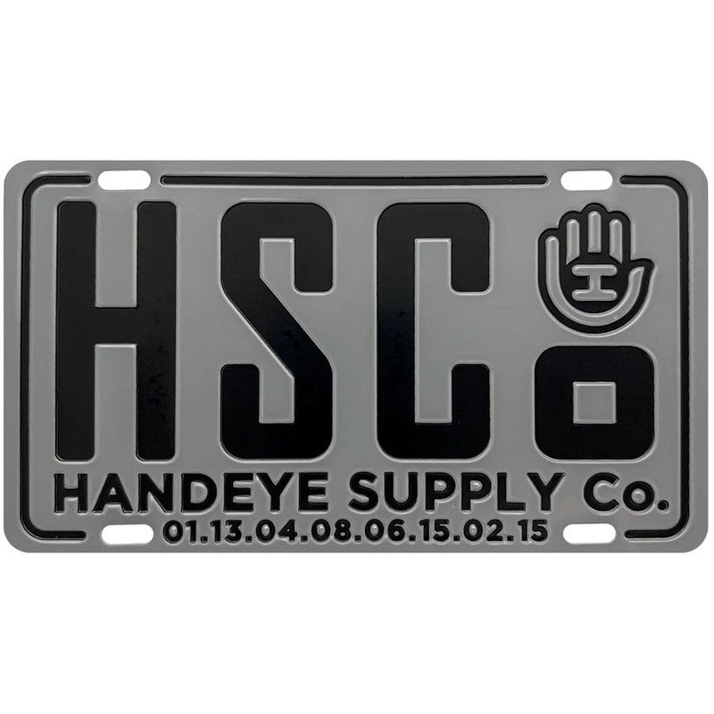 Gray Handeye Suppy Co. HSC mini metal license plate with a black logo, black text, and four holes for mounting.