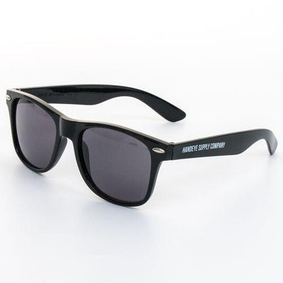 Black Handeye Supply Company sunglasses with dark gray lenses and silver hardware on a white background.
