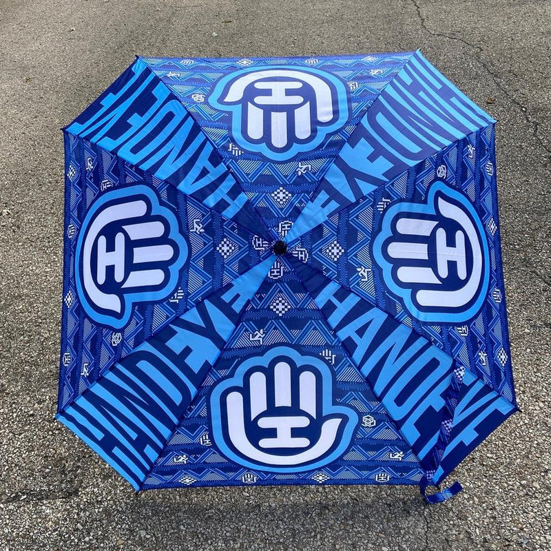 Handeye Supply Co Arc Umbrella in dark blue with light blue hand logos and text patterns across its surface.