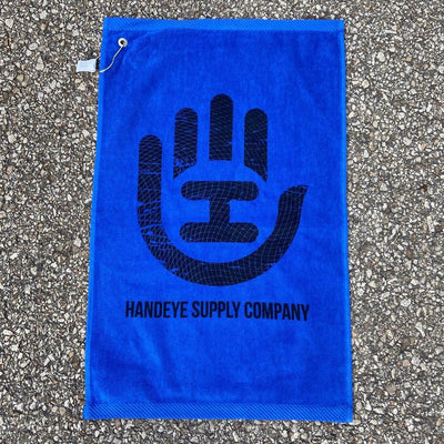 Bright blue Handeye Supply Company disc golf towel featuring a large black hand logo and a hanging loop.