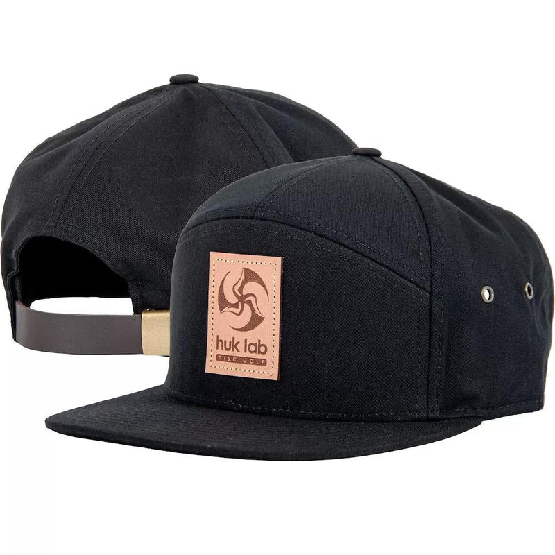 Two black Huk Lab Trifly hats feature a light brown leather patch with a darker brown swirl logo and text.