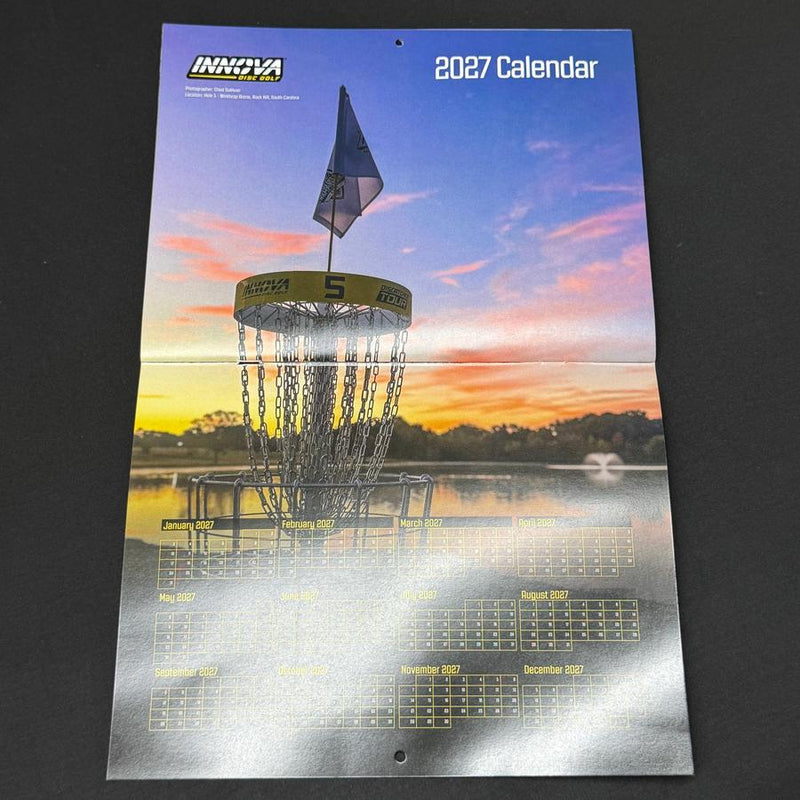 Innova 2027 calendar featuring a disc golf basket with a flag on black paper, displaying monthly grids.