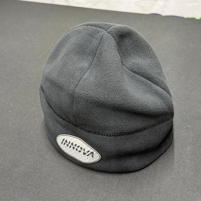 Black fleece beanie with a white oval Innova logo patch featuring black lettering and neatly stitched seams.
