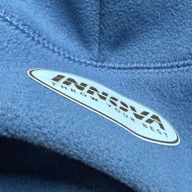 Blue fleece beanie with a white oval Innova patch that says "THROW YOUR BEST" in brown lettering.
