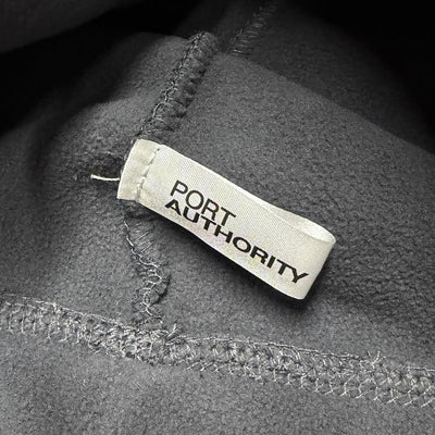 Dark gray fleece beanie with a white "PORT AUTHORITY" brand tag stitched on the side.