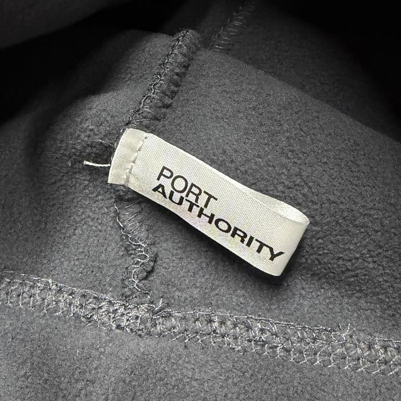 Dark gray fleece beanie with a white "PORT AUTHORITY" brand tag stitched on the side.