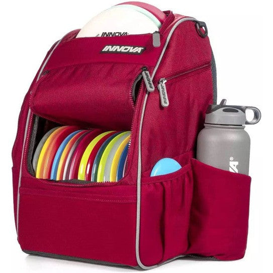 Cherry red Innova Excursion Pack disc golf bag with colorful discs and a gray water bottle in the side pocket.